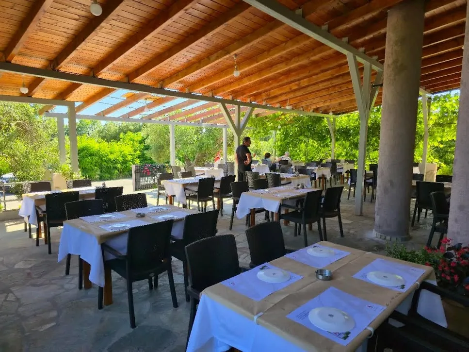 Tables beneath the timber-roofed dining terrace at To Steki Tou Mpampi in Mola Kalyva.